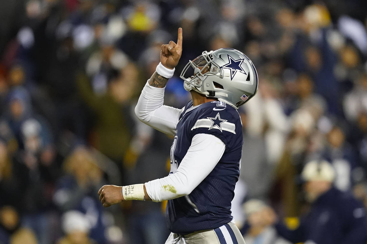 FILE - Dallas Cowboys quarterback Dak Prescott (4) points upward after scoring against Washington C...