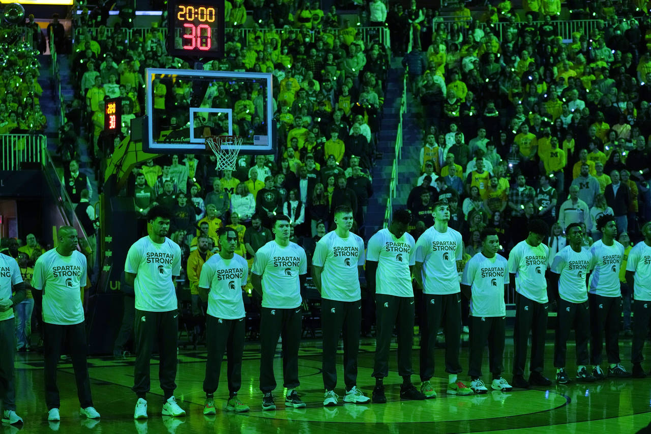The Michigan State team stands during a moment of silence before the first half of an NCAA college ...