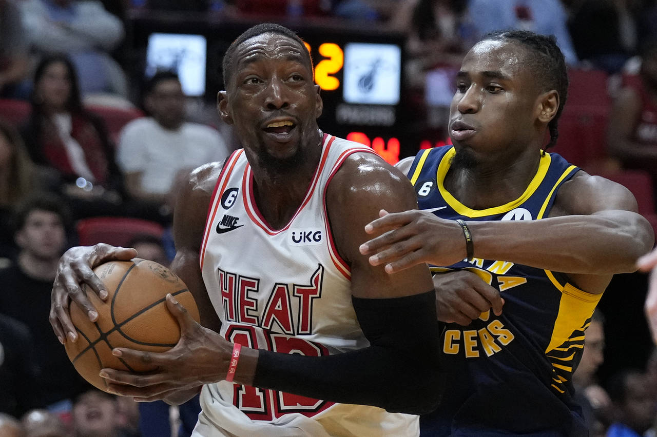 Miami Heat center Bam Adebayo, left, drives to the basket against Indiana Pacers guard Aaron Nesmit...