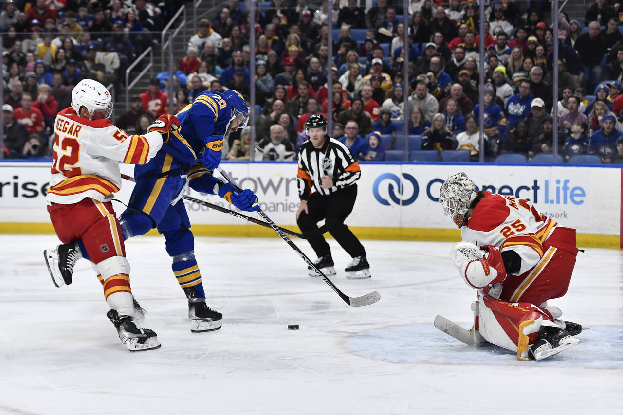 Buffalo Sabres left wing Zemgus Girgensons, center, is tied up with Calgary Flames defenseman MacKe...