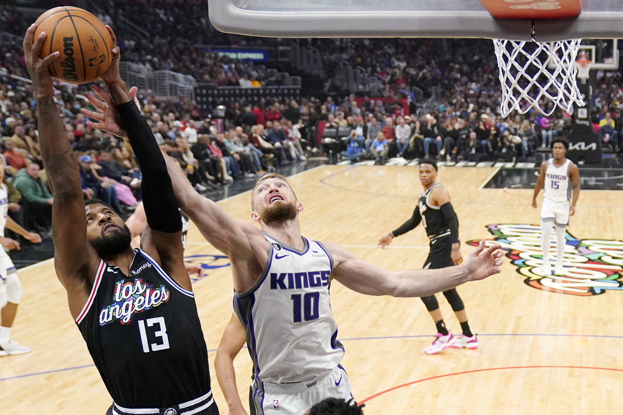 Los Angeles Clippers forward Paul George, left, grabs a rebound away from Sacramento Kings forward ...