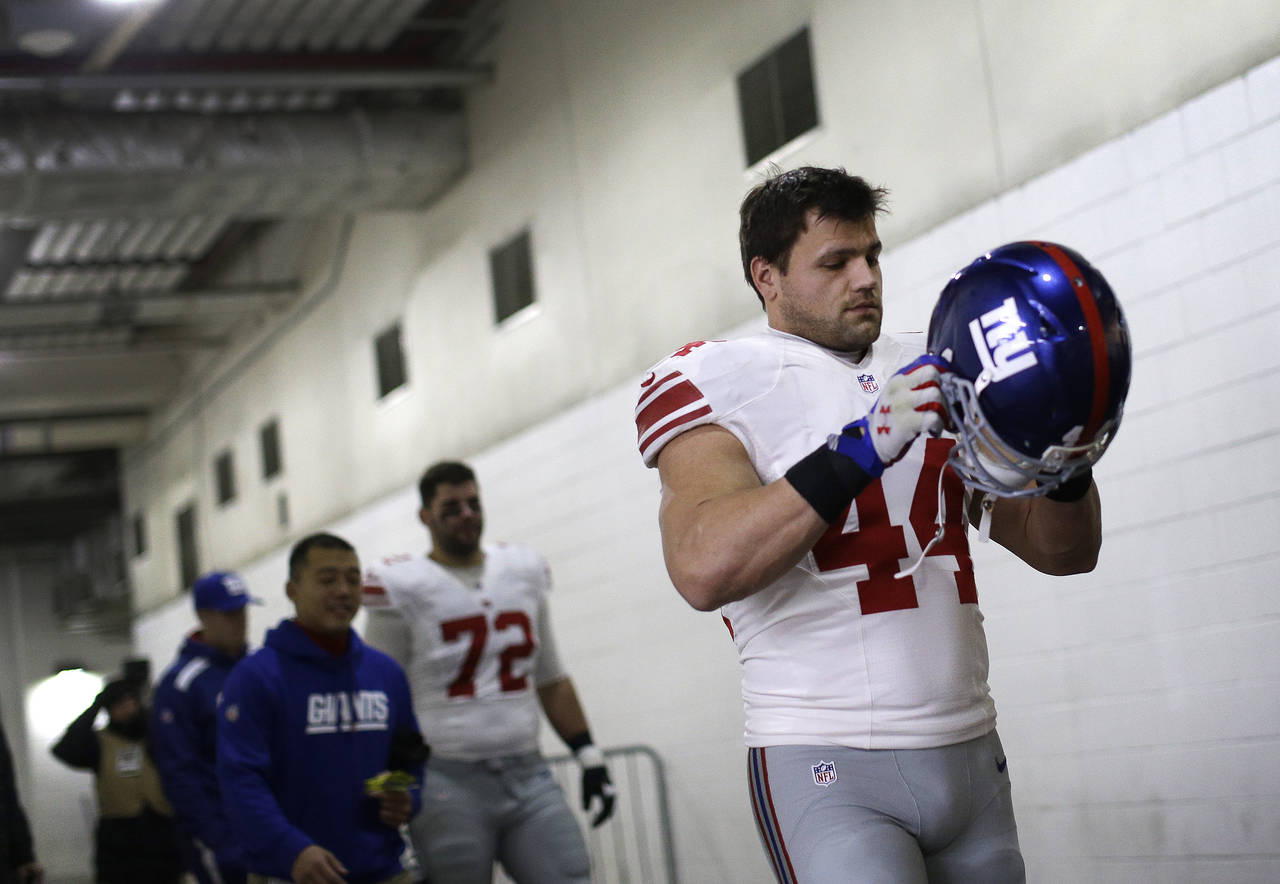 FILE - New York Giants running back Peyton Hillis puts his helmet on as he walks through a tunnel t...
