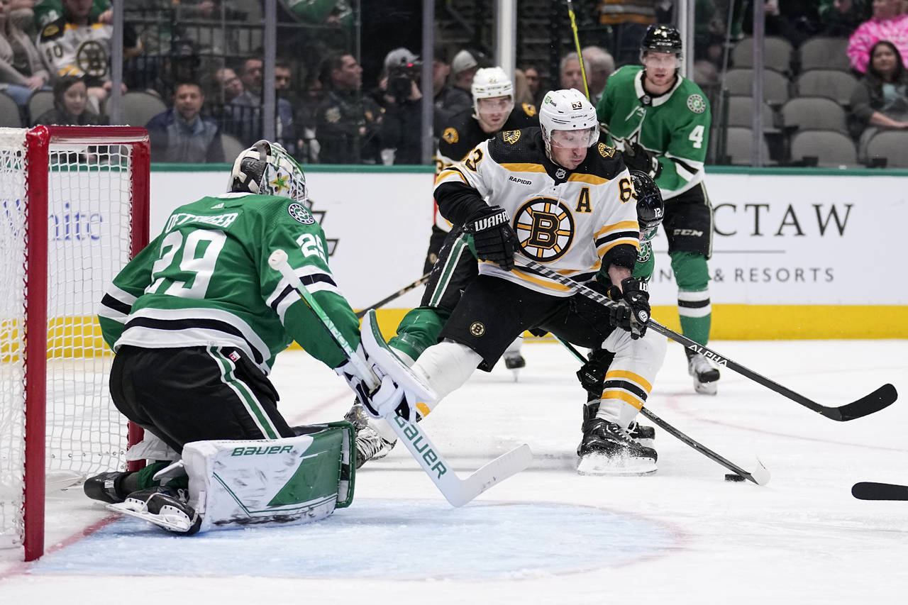 Dallas Stars goaltender Jake Oettinger (29) defends as Boston Bruins left wing Brad Marchand (63) a...