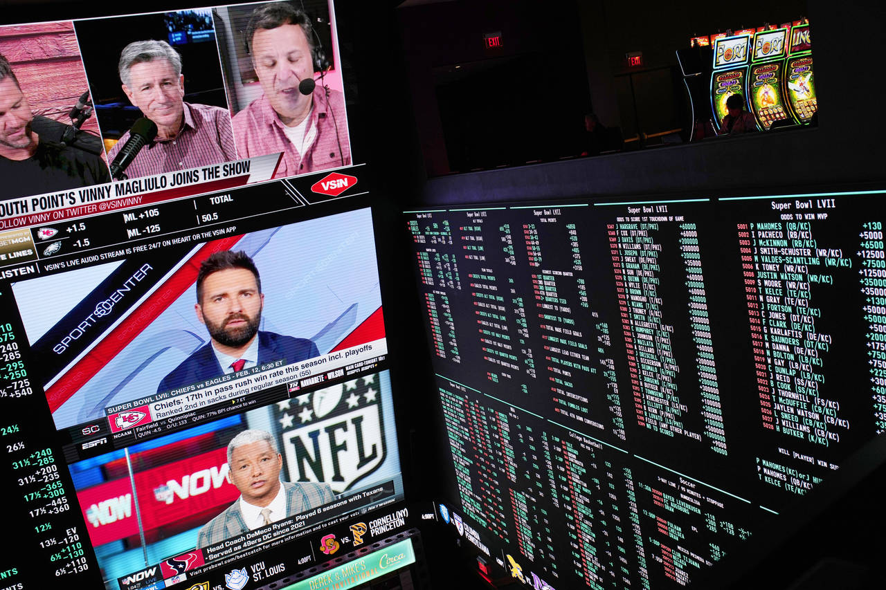A person gambles as betting odds for NFL football's Super Bowl are displayed on monitors at the Cir...