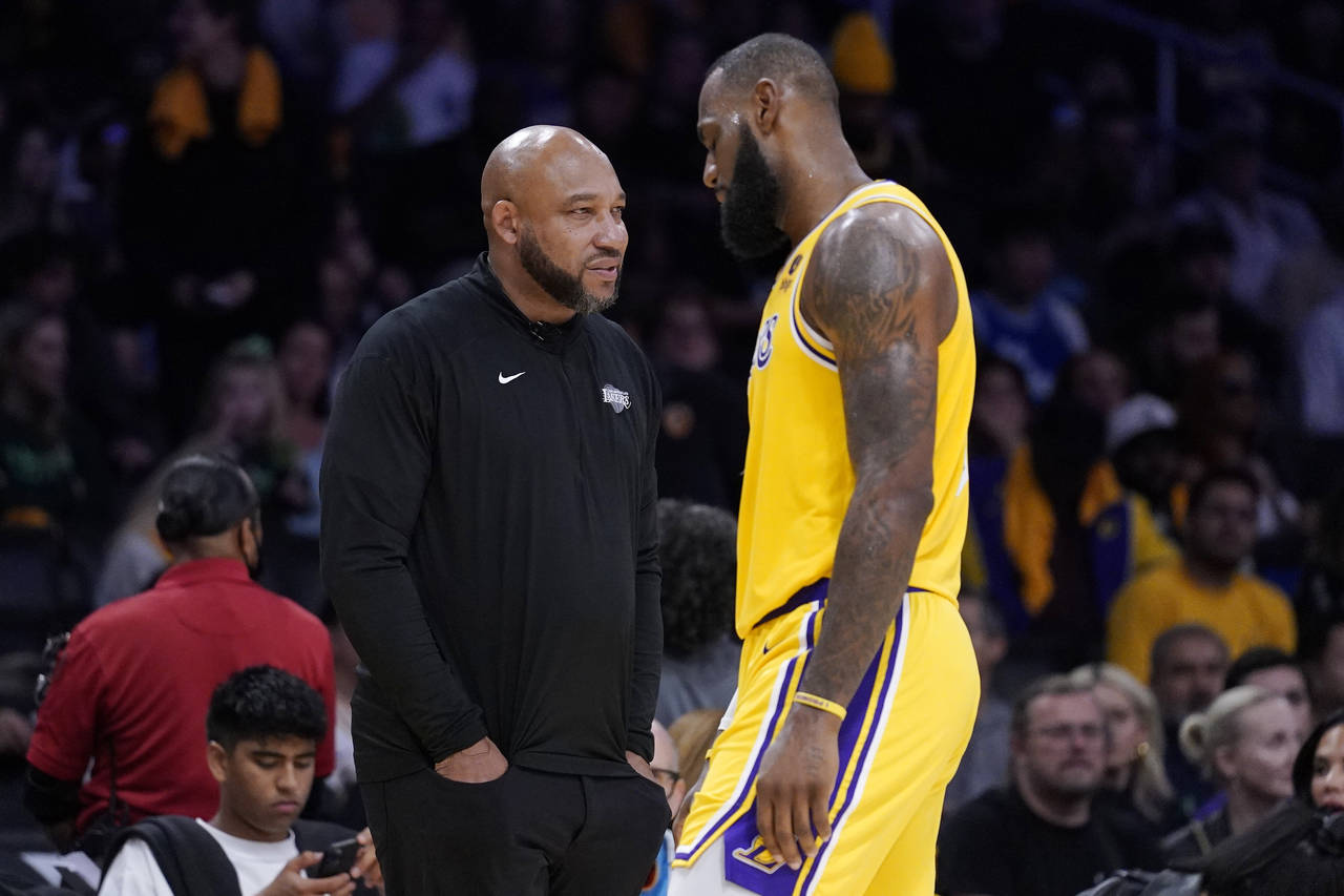 FILE - Los Angeles Lakers forward LeBron James, right, walks back to the bench as head coach Darvin...