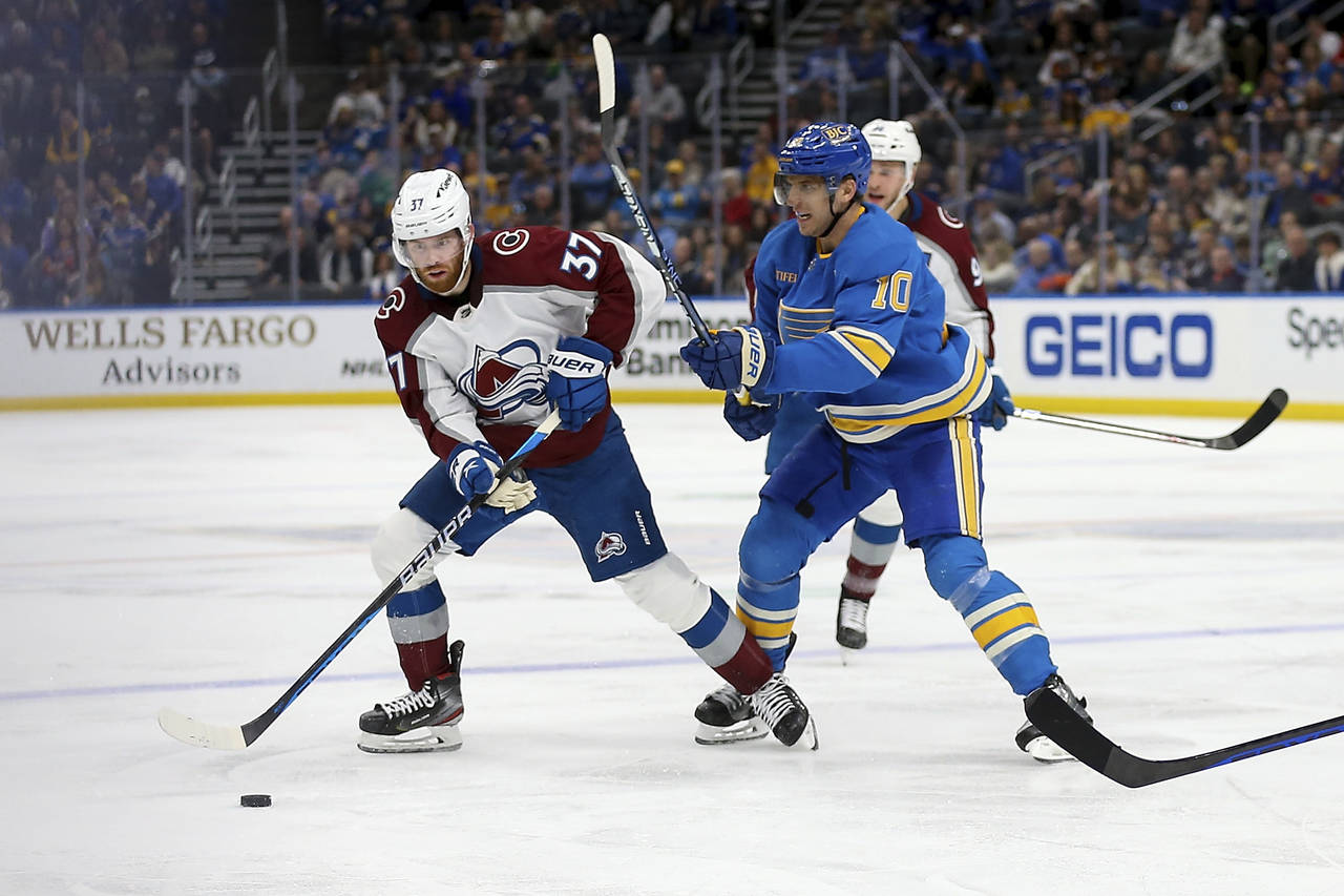Colorado Avalanche's J.T. Compher (37) looks to pass the puck while under pressure from St. Louis B...