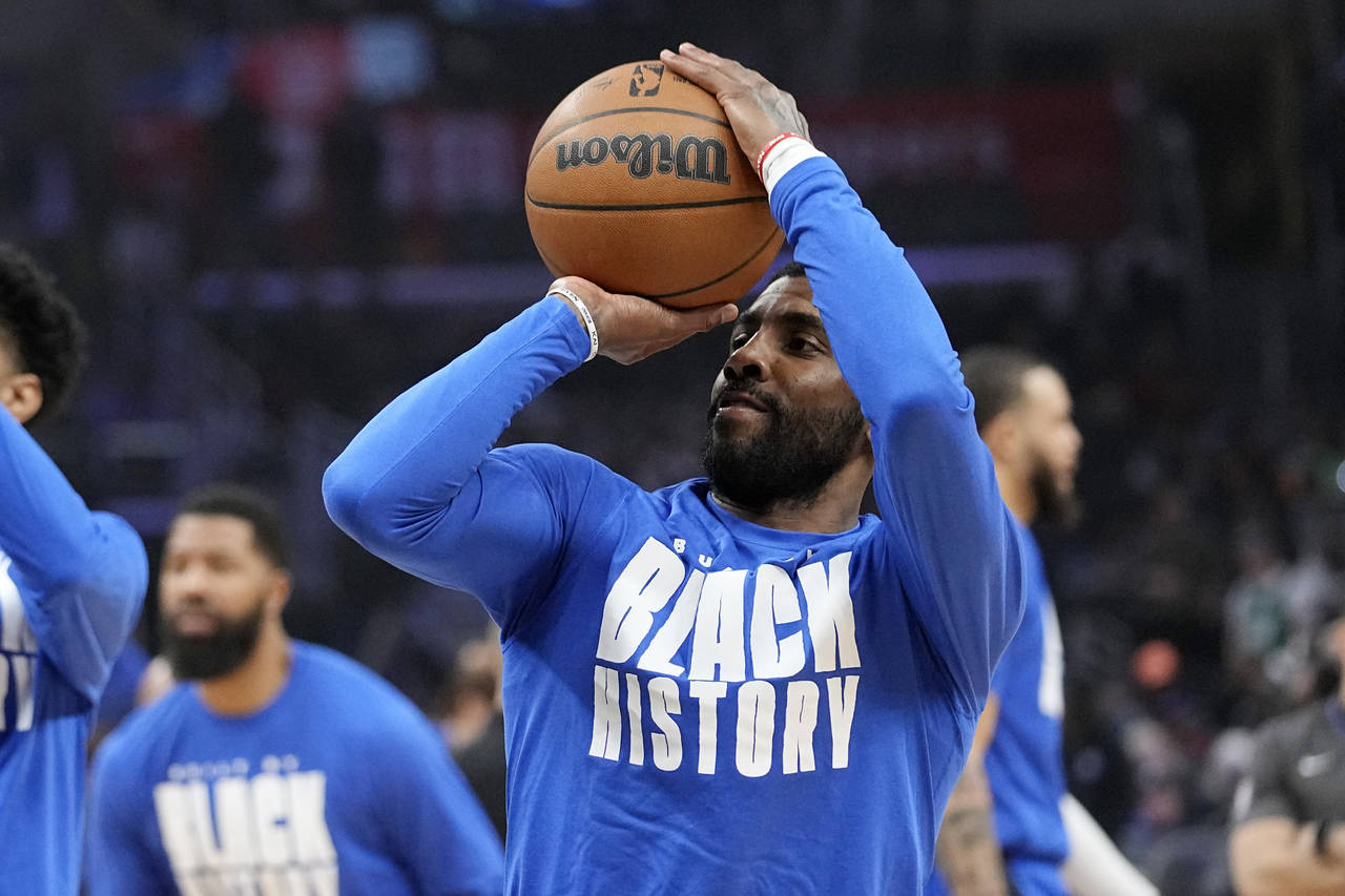 Dallas Mavericks guard Kyrie Irving smiles as he warms up prior to an NBA basketball game against t...