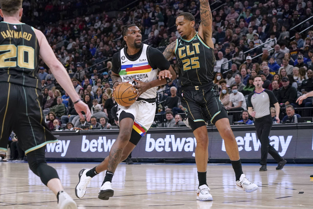 Minnesota Timberwolves center Naz Reid, center, drives past Charlotte Hornets forward P.J. Washingt...