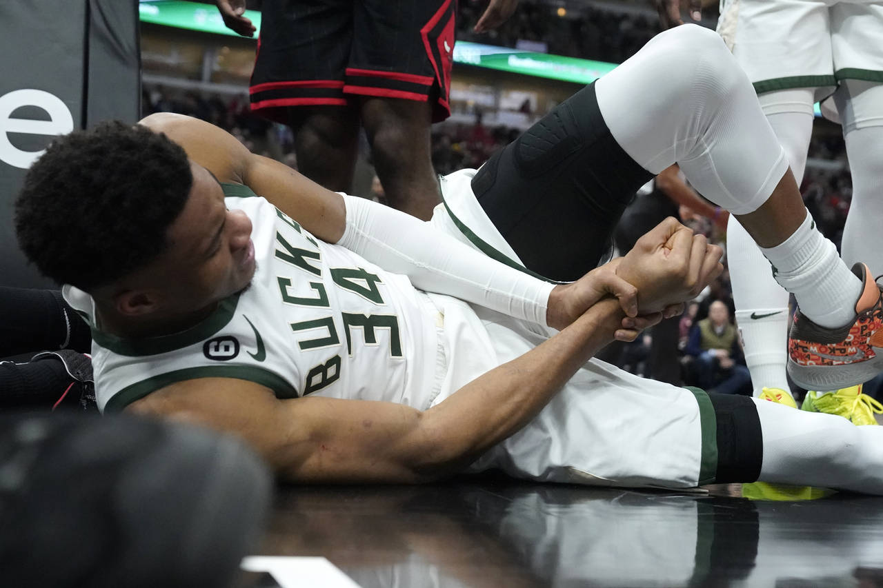 Milwaukee Bucks' Giannis Antetokounmpo lies by the basket after injuring his right wrist during the...