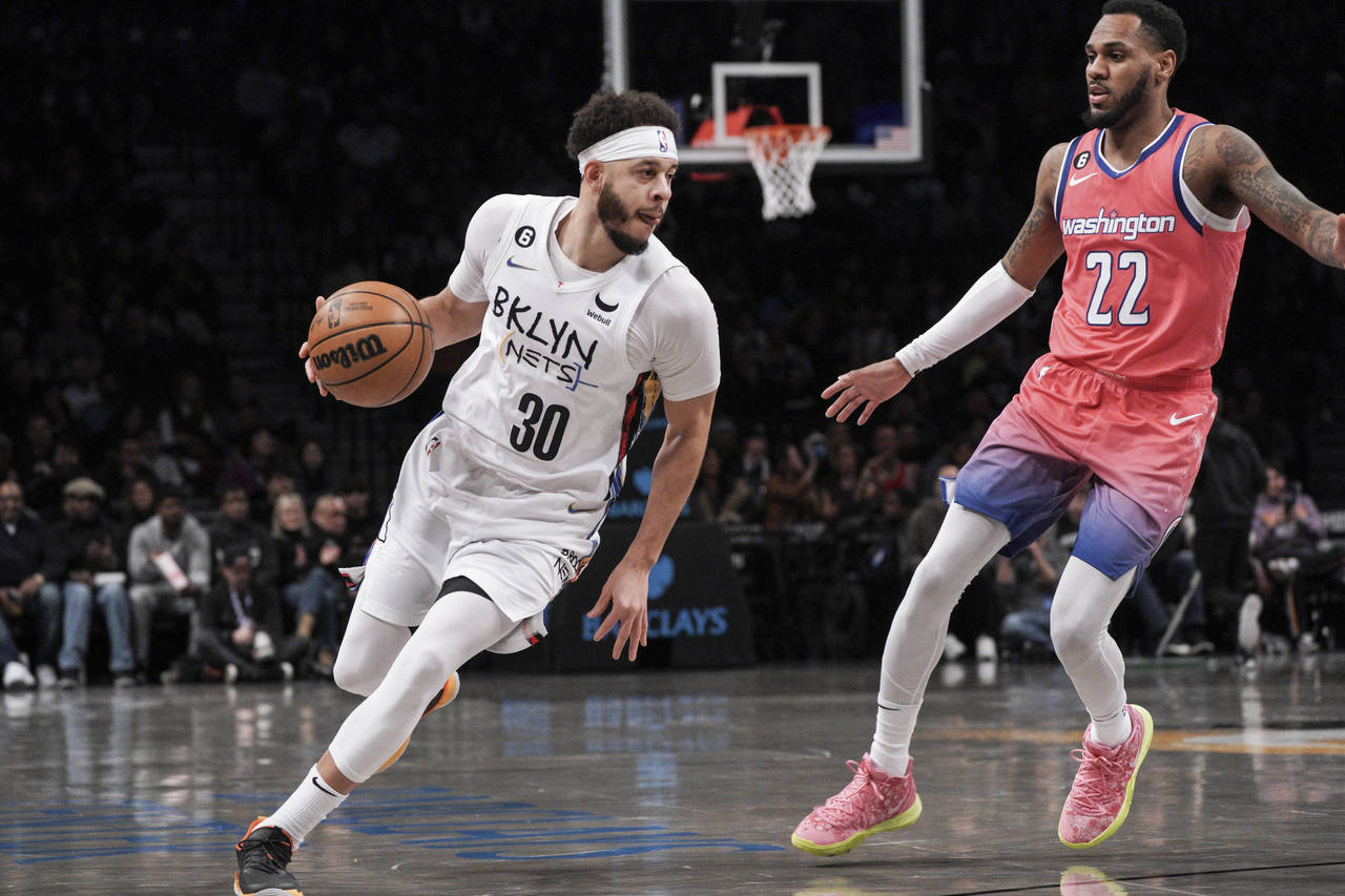Brooklyn Nets guard Seth Curry, left, drives to the basket against Washington Wizards guard Monte M...