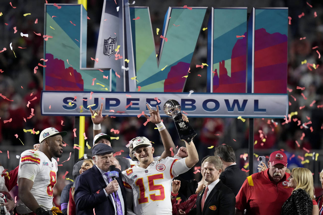 Kansas City Chiefs quarterback Patrick Mahomes (15) holds the Vince Lombardi Trophy while talking t...
