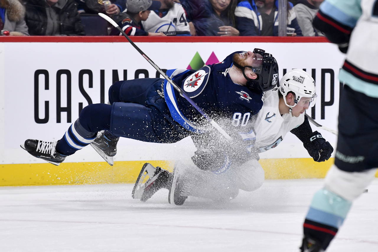 Seattle Kraken's Eeli Tolvanen (20) dumps Winnipeg Jets' Pierre-Luc Dubois (80) during the second p...