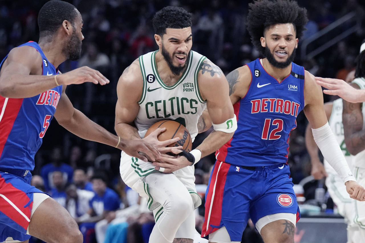 Boston Celtics forward Jayson Tatum (0) drives through Detroit Pistons guard Alec Burks, left, and ...