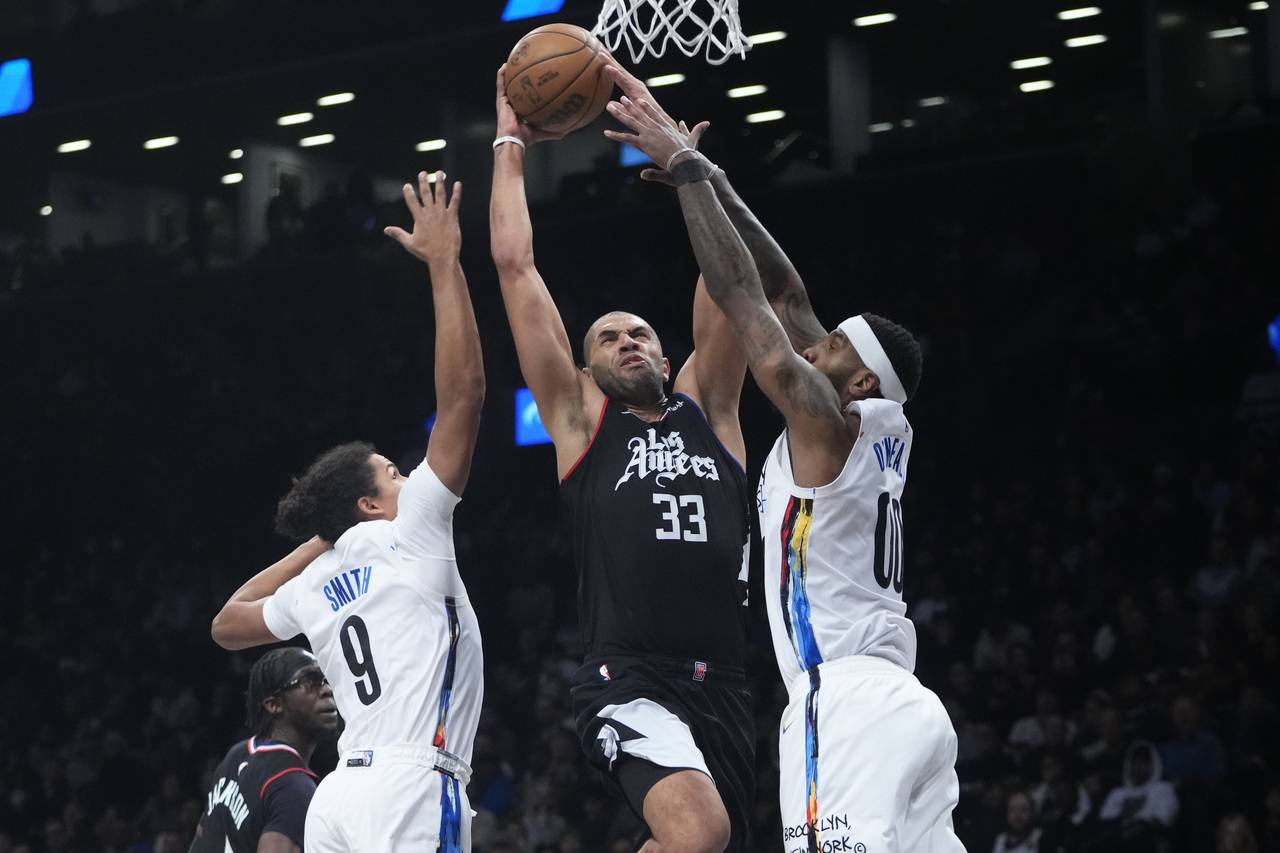Los Angeles Clippers' Nicolas Batum (33) is defended by Brooklyn Nets' Dru Smith (9) and Royce O'Ne...