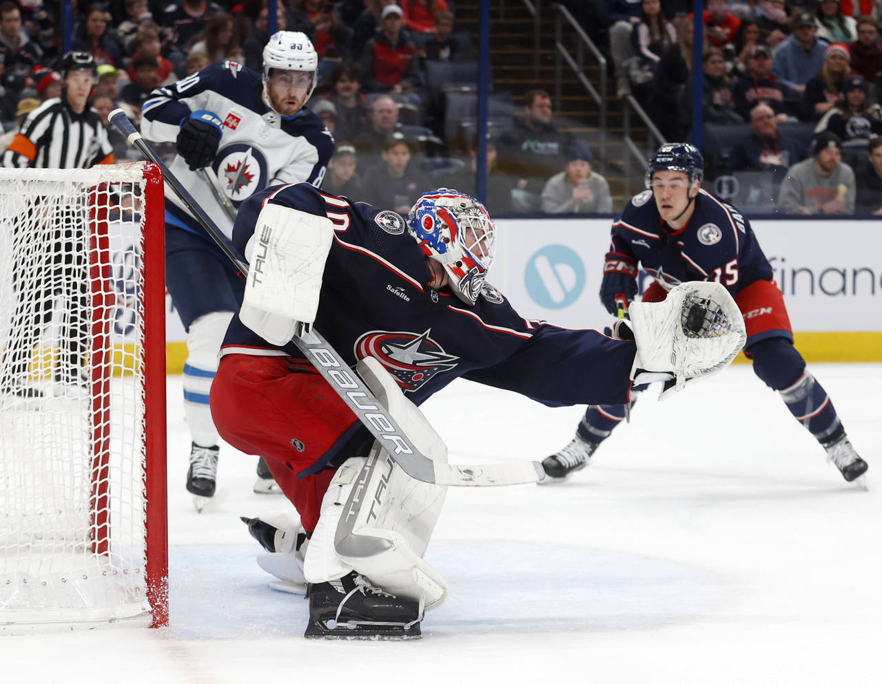 Columbus Blue Jackets goalie Joonas Korpisalo, center, makes a stop in front of Winnipeg Jets forwa...
